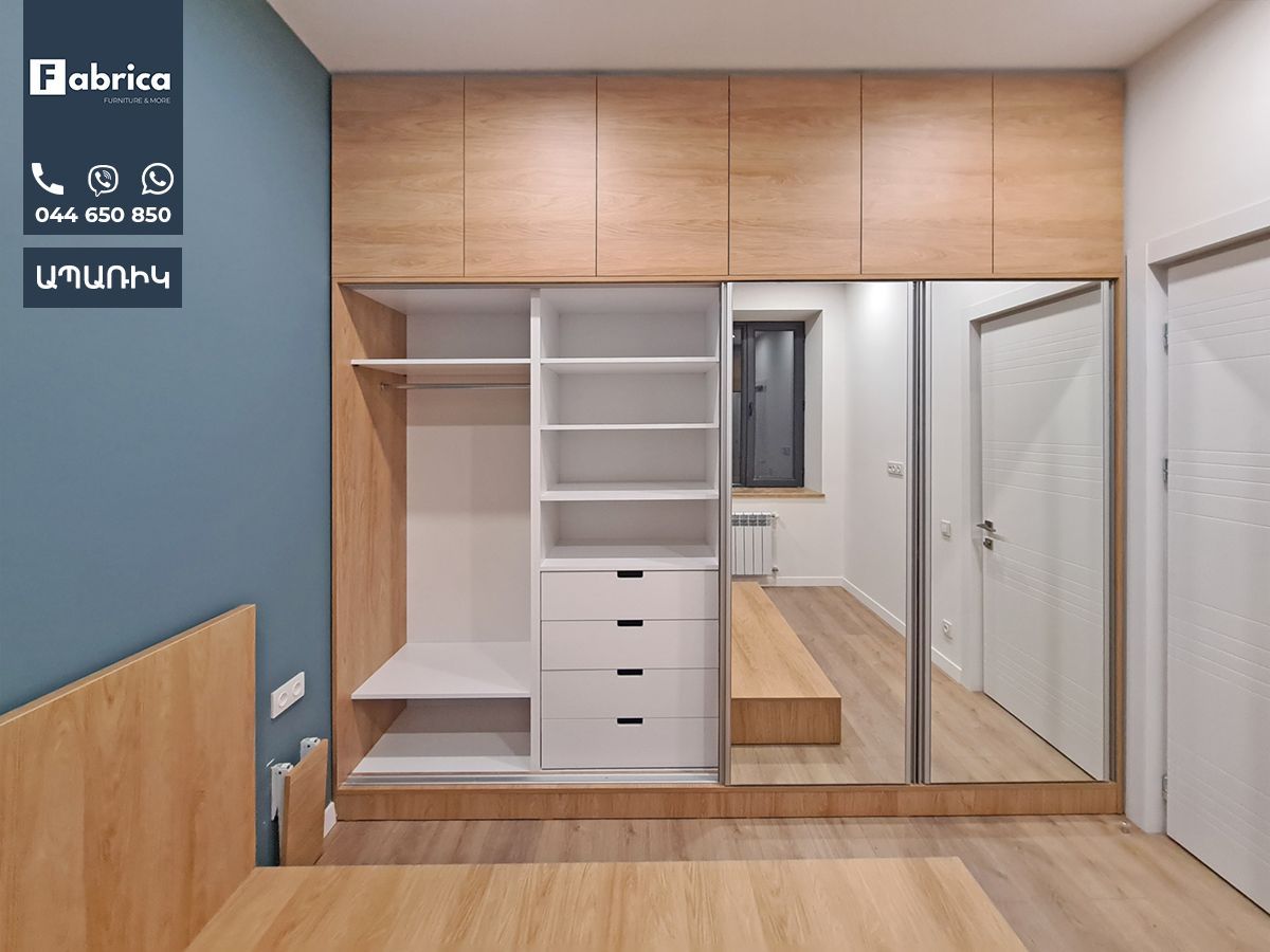 A bedroom with wooden cabinets and a large mirror