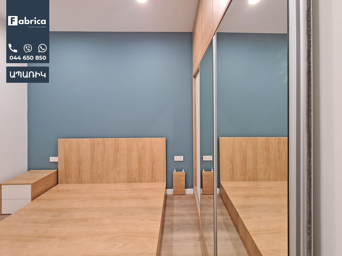 A bedroom with a bed and a mirror on the wall.