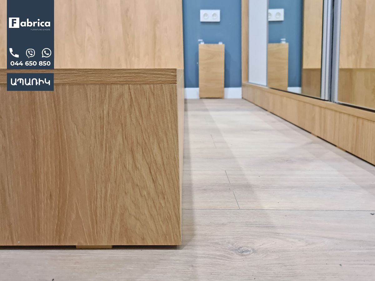 A wooden box is sitting in a room next to a mirror.