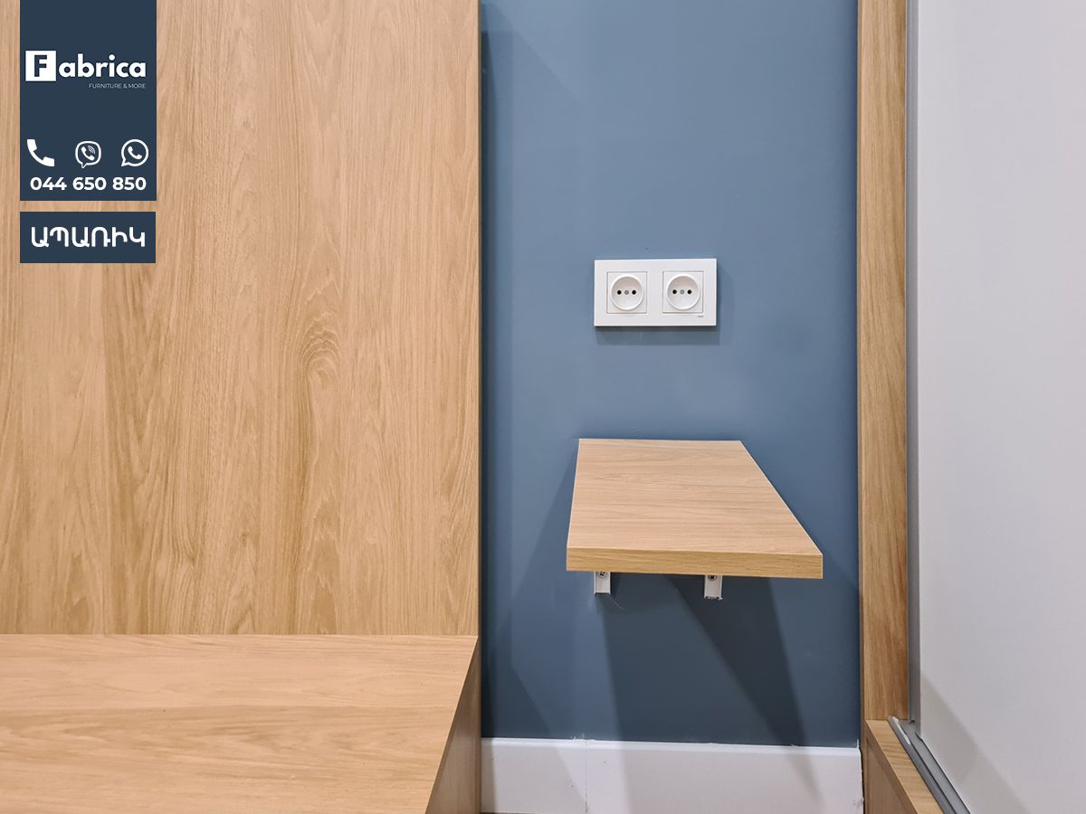 A wooden shelf is hanging on a wall next to a blue wall.