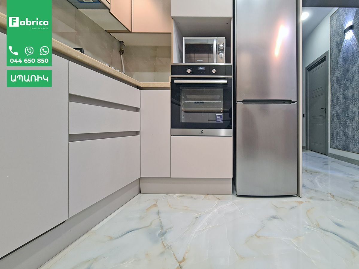 A kitchen with white cabinets and a stainless steel refrigerator
