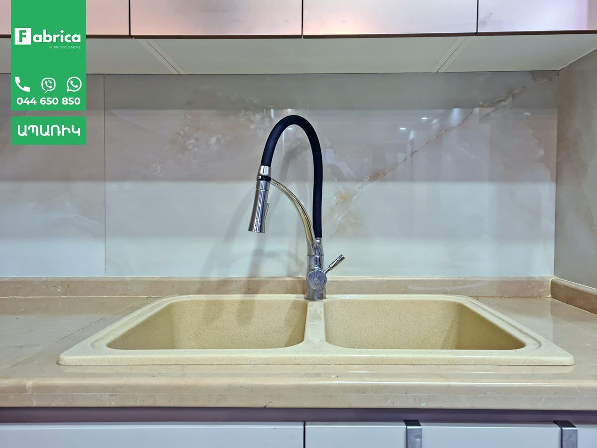A kitchen sink with a black faucet and a green sign that says fabrice