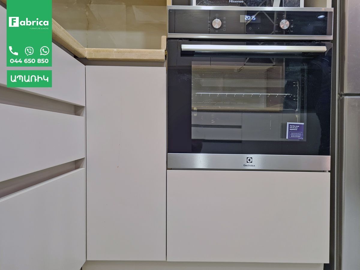 A stainless steel oven is sitting in a kitchen next to a refrigerator.
