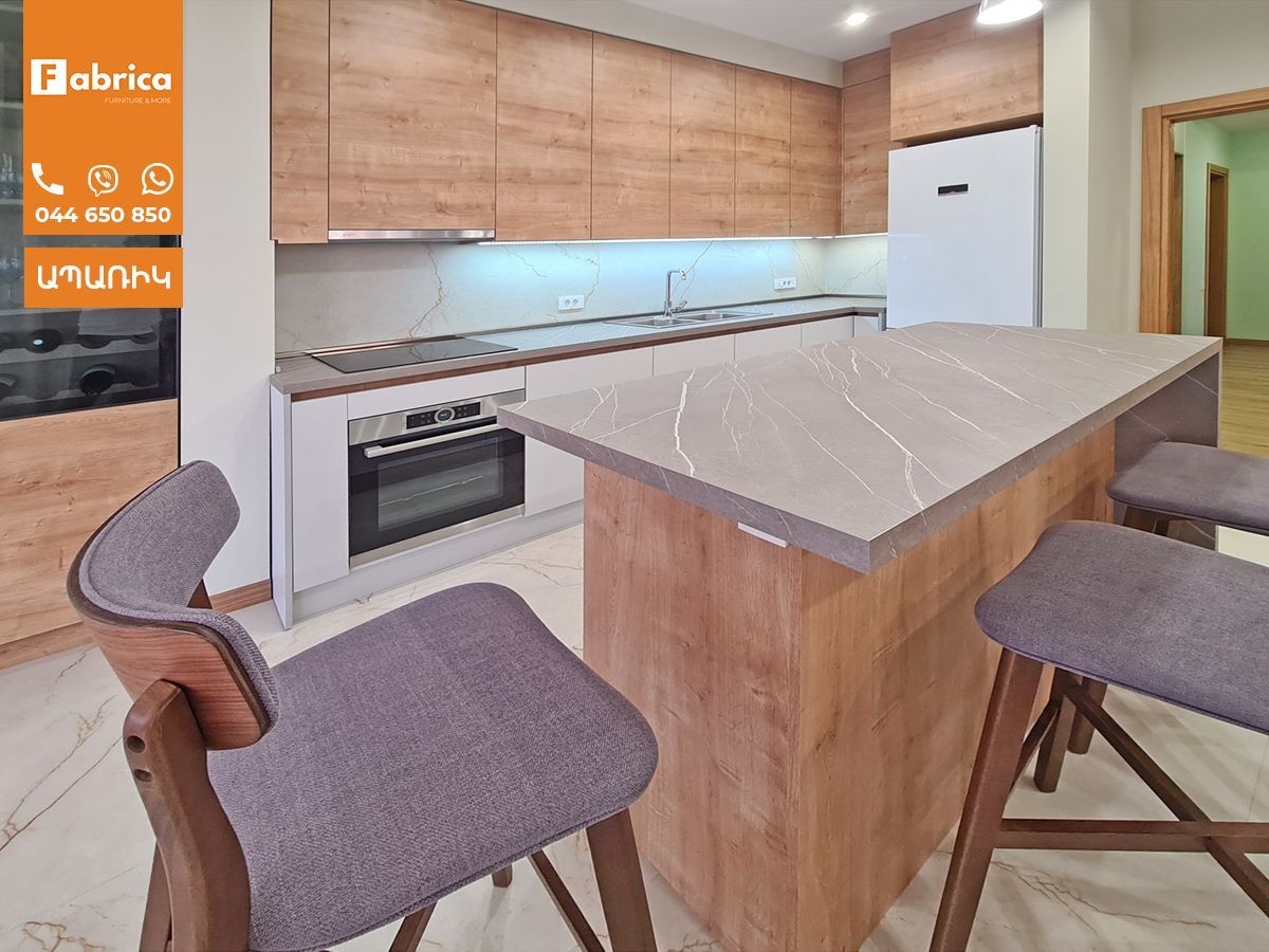 A kitchen with wooden cabinets and a marble counter top