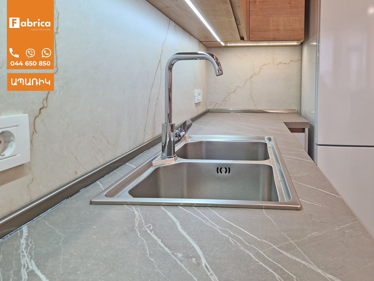 A kitchen with a stainless steel sink and a faucet