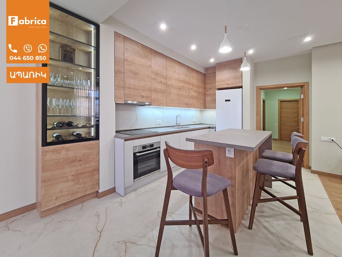 A kitchen with wooden cabinets , a stove , a refrigerator and a bar.