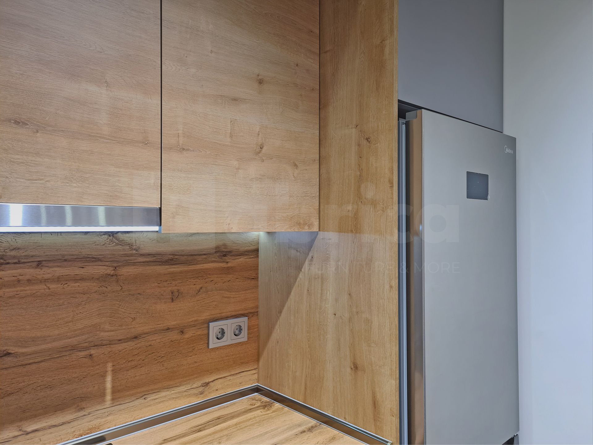 A kitchen with wooden cabinets and a stainless steel refrigerator.