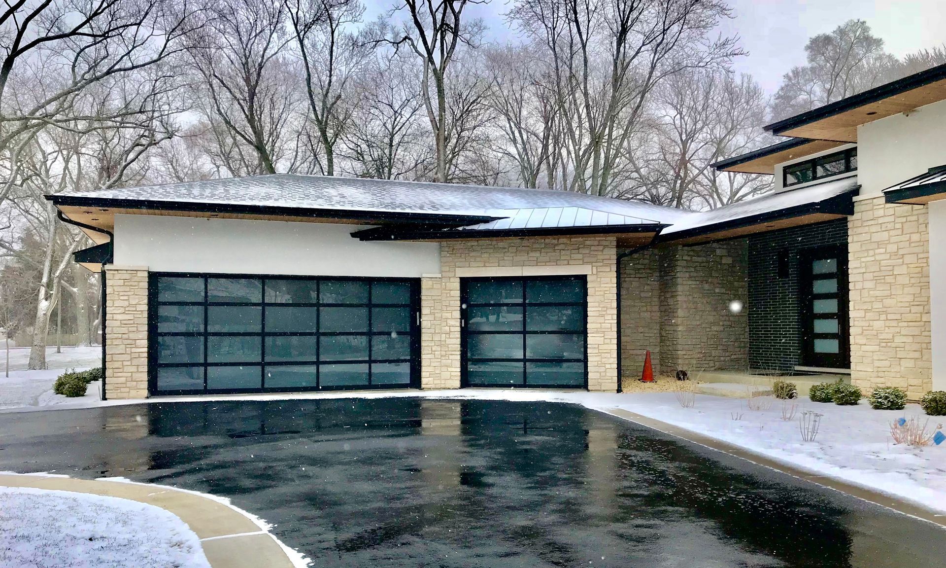 Interior view of an open garage door; white panel door on metal tracks attached to brick and cement walls.