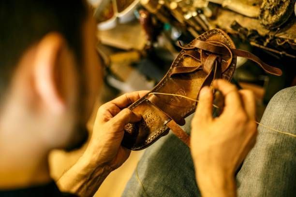 A man is making a pair of shoes in a workshop.