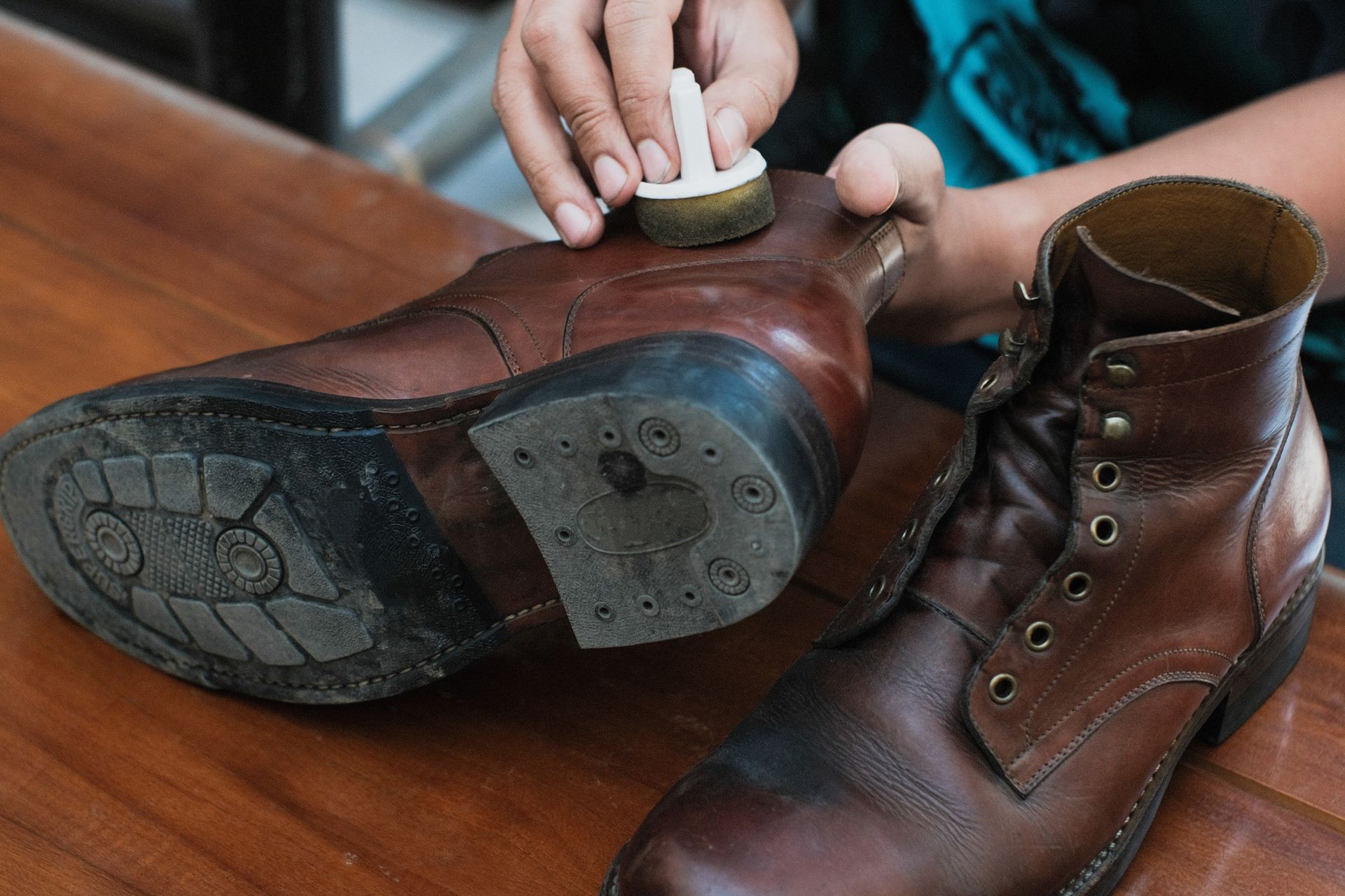 A person is cleaning a pair of brown boots with a brush.