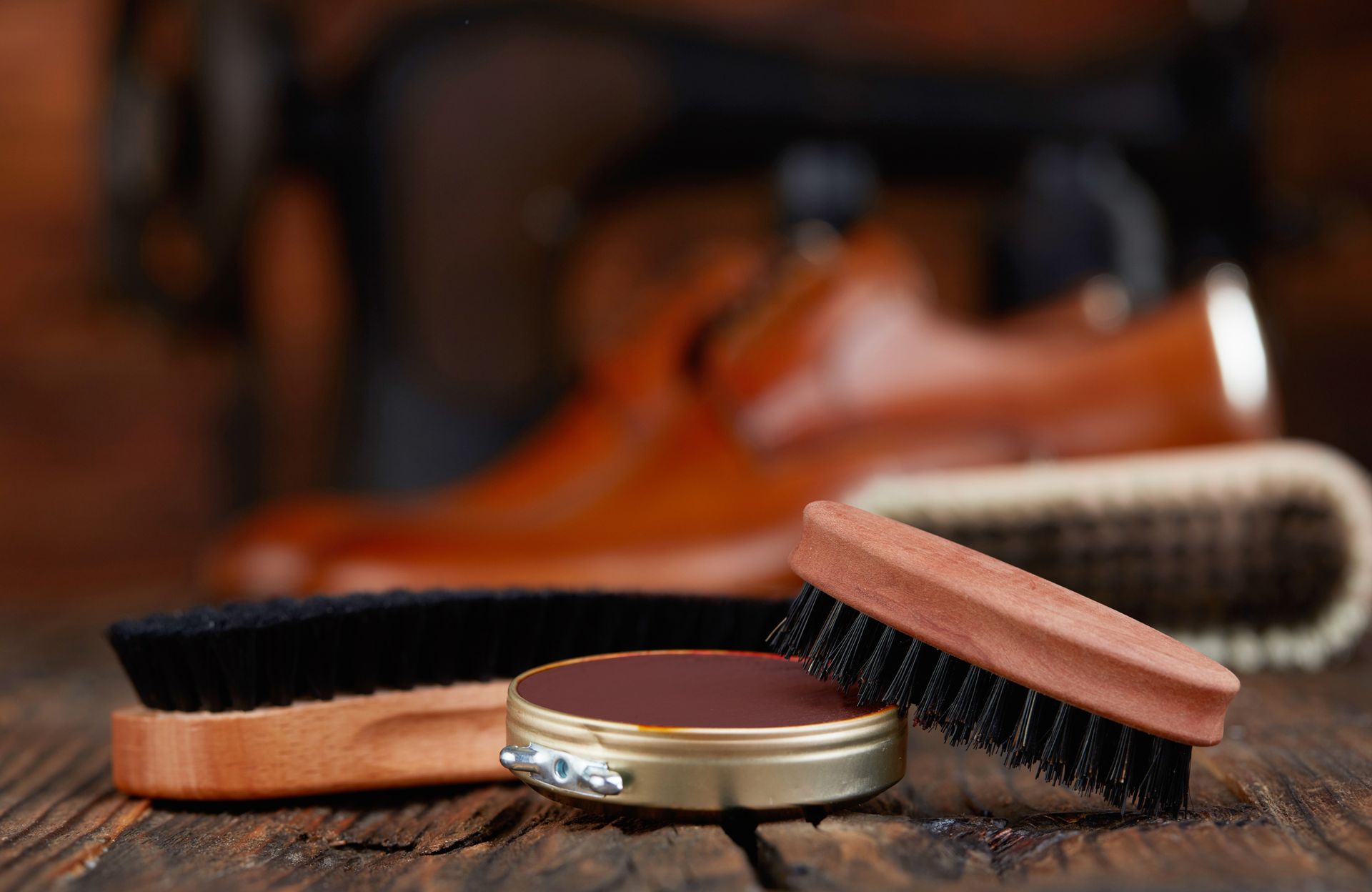 A wooden table topped with brushes , polish and a pair of shoes.