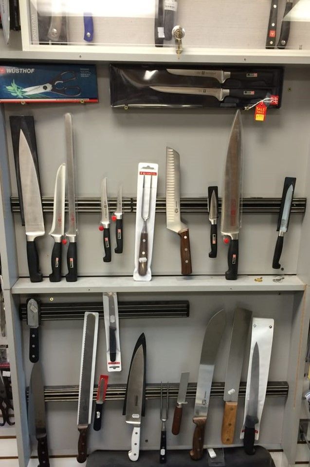 A bunch of knives are lined up on a shelf