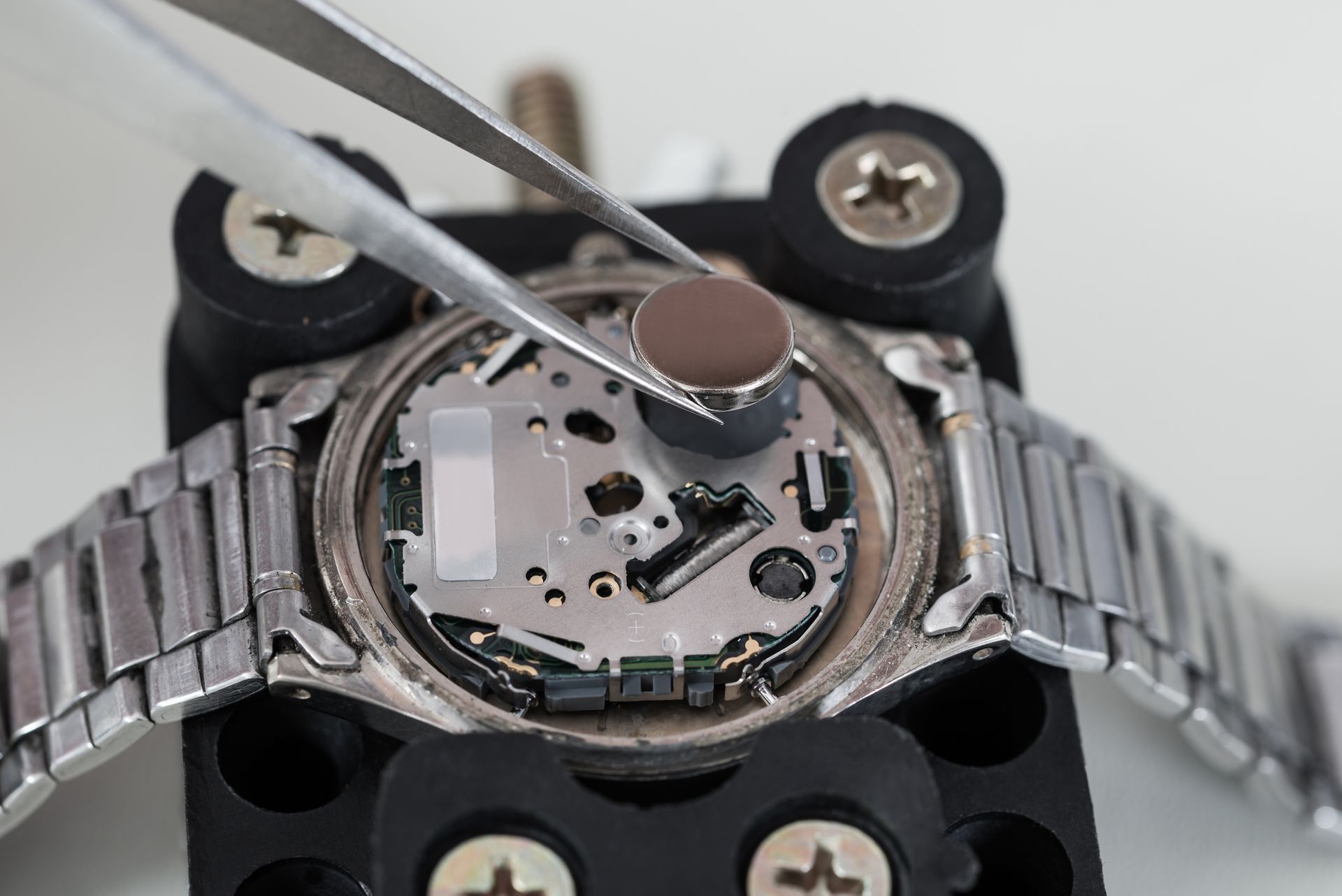 A close up of a watch being repaired with tweezers.