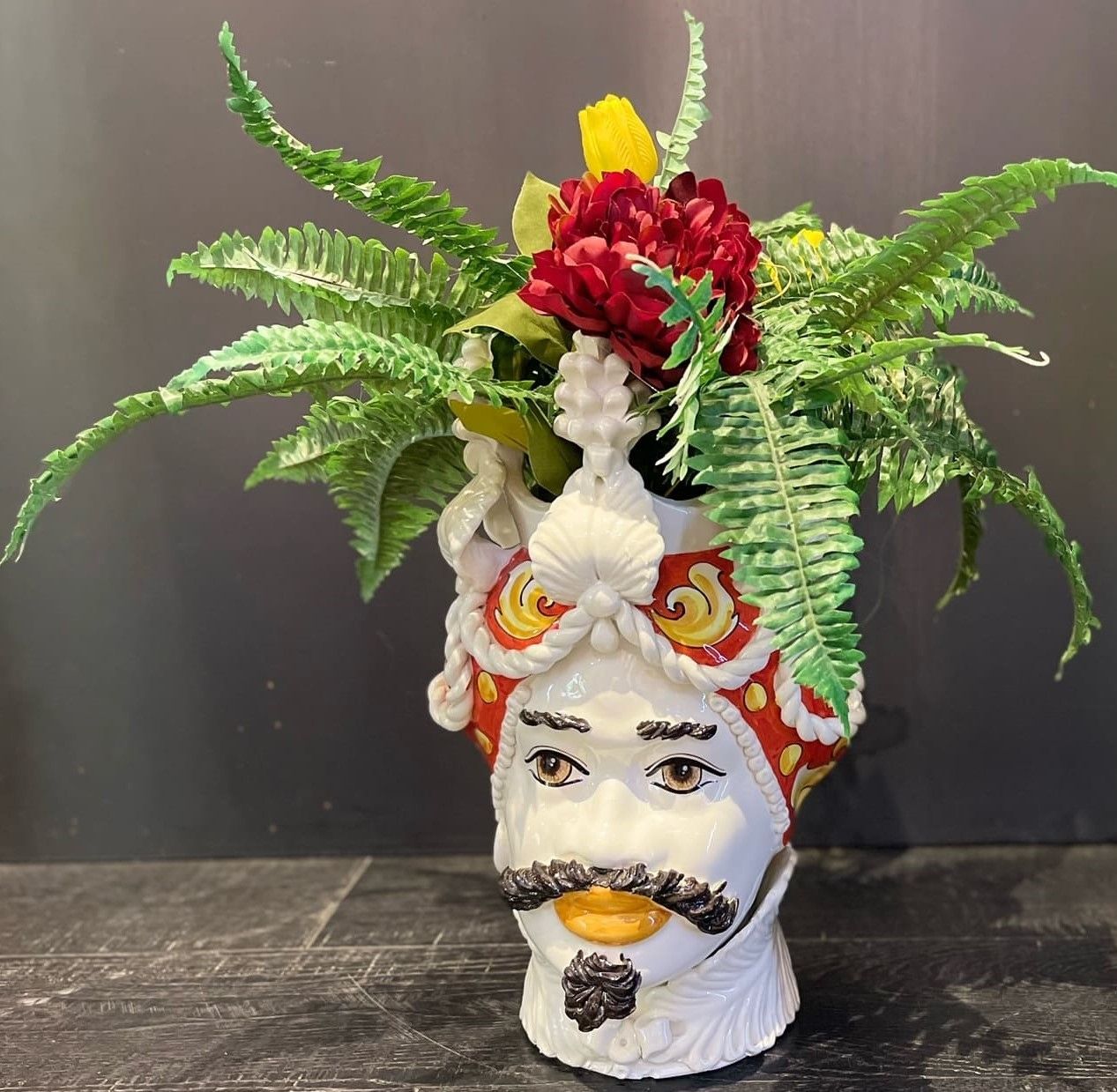 Un vaso a forma di testa d'uomo con fiori al suo interno