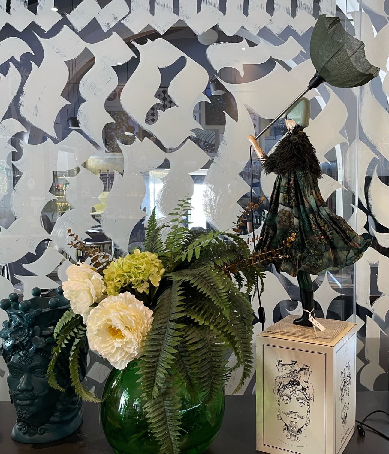 Un vaso di fiori è appoggiato su un tavolo accanto a una lampada