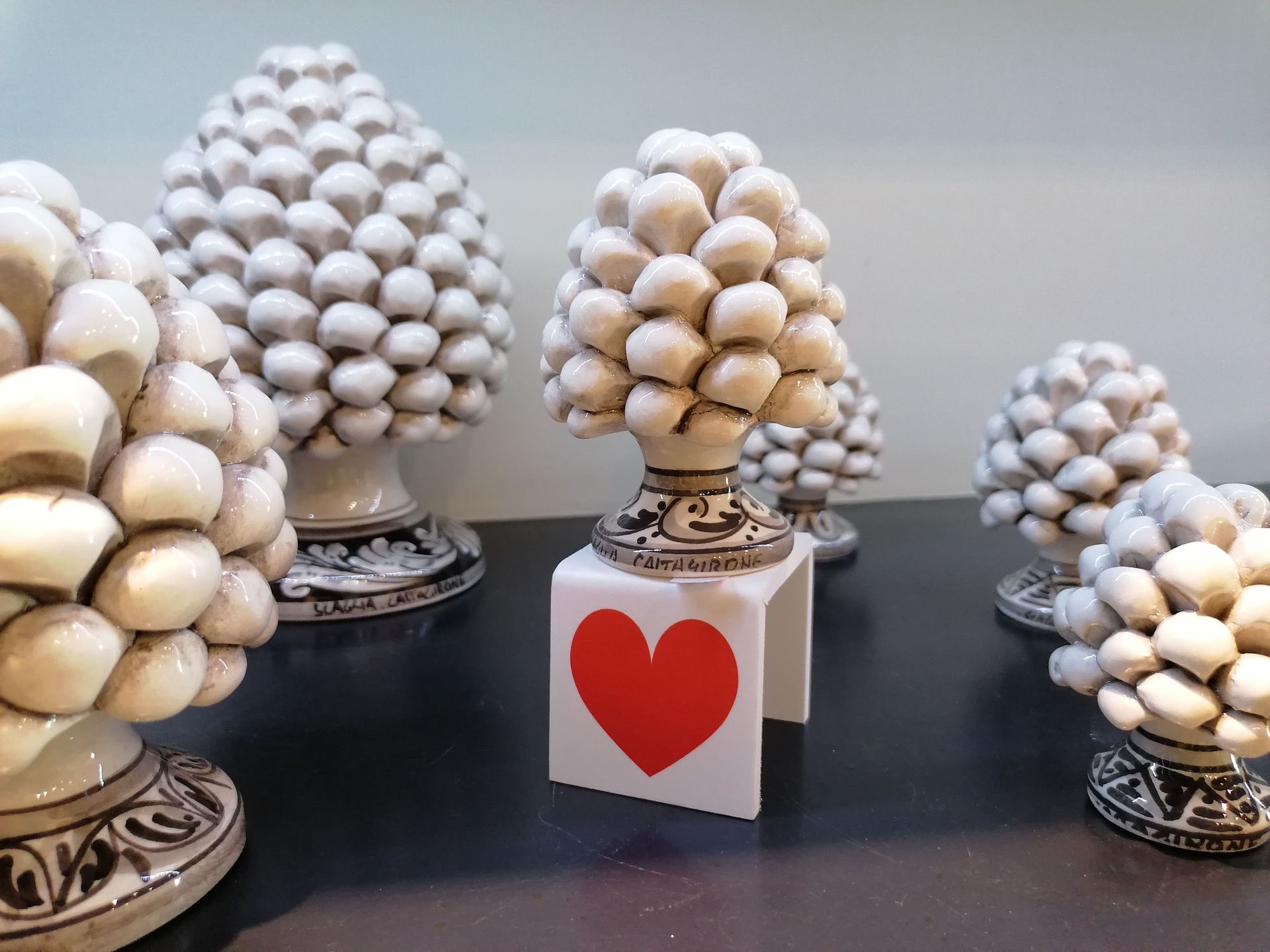 Un gruppo di pigne è appoggiato su un tavolo accanto a un biglietto con un cuore sopra.