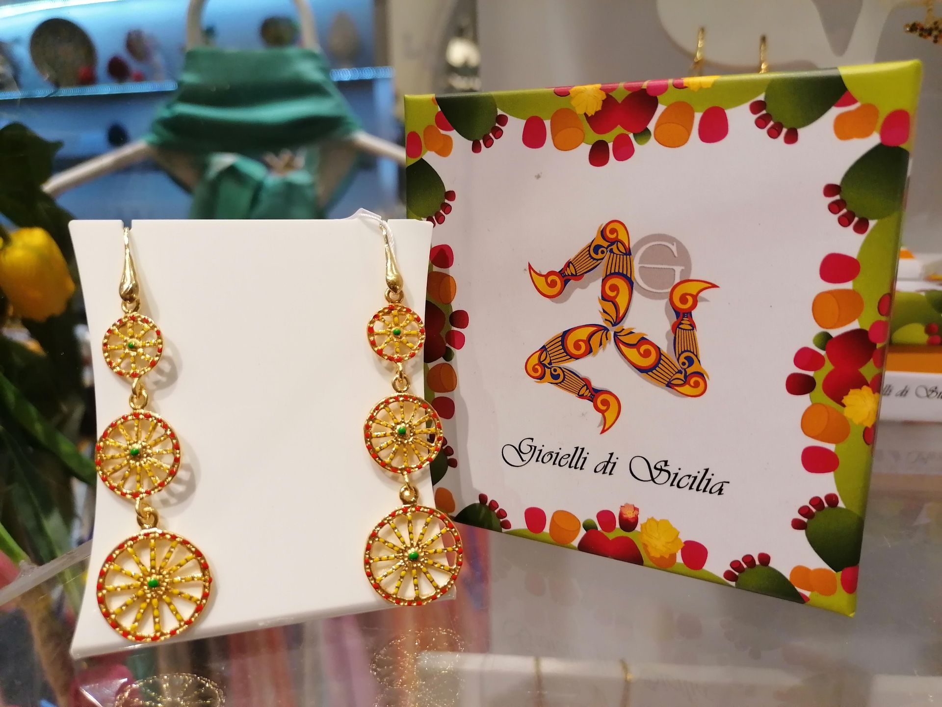 Un paio di orecchini accanto a un cartellino con scritto  gioielli  di  sicilia 