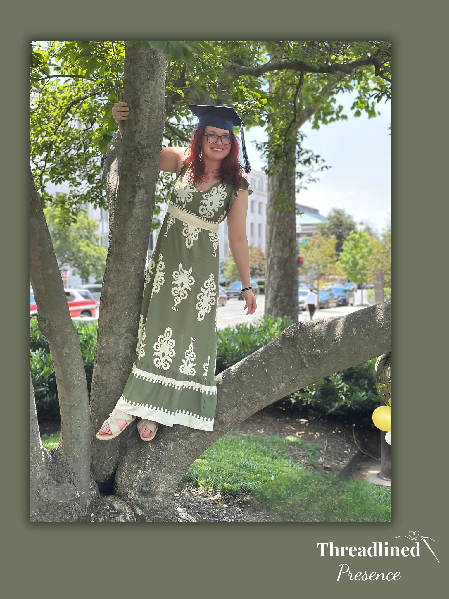 Photo of Bernice wearing a graduation cap while smiling in a tree