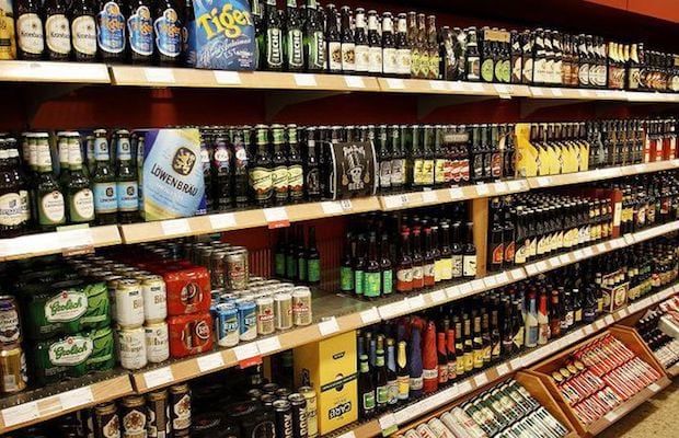 A grocery store aisle filled with lots of beer bottles and cans.