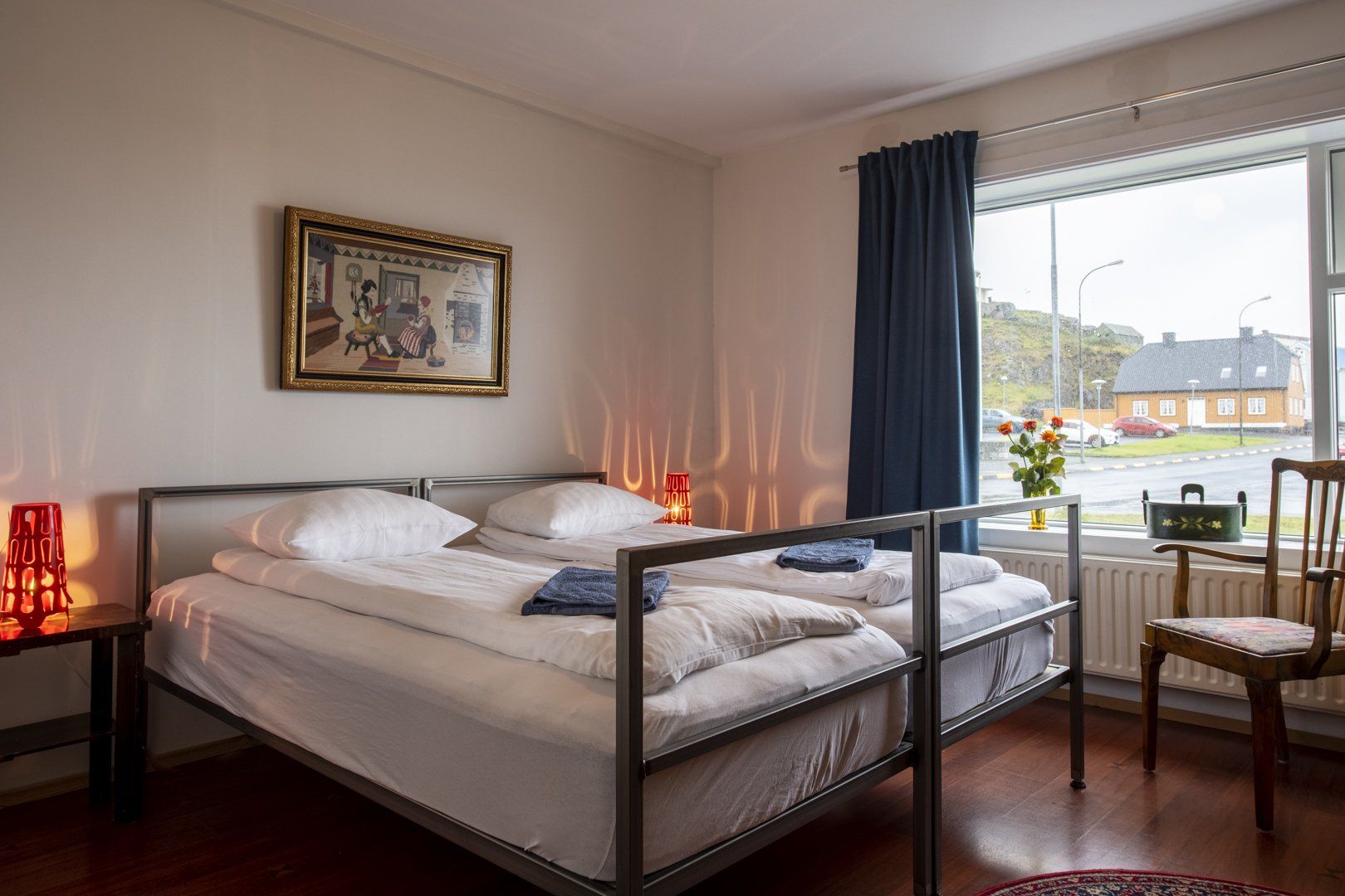 A bedroom with two beds , a chair , a table and a window.