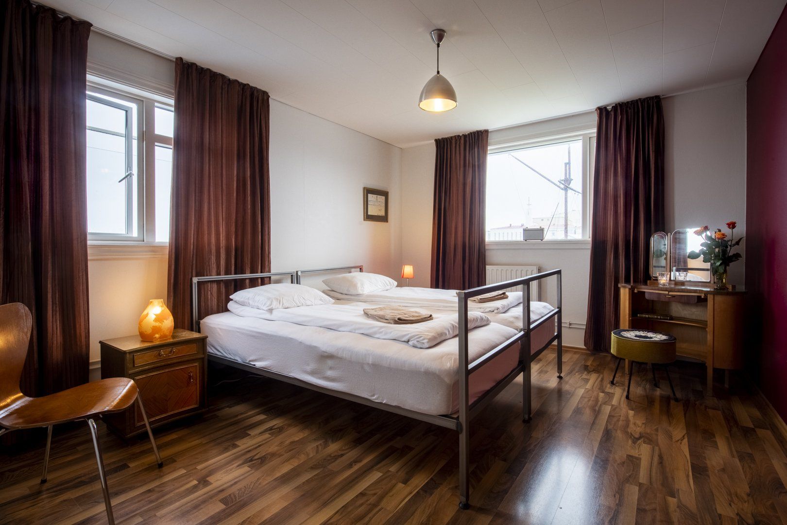 A bedroom with two beds , a chair , a desk and a window.