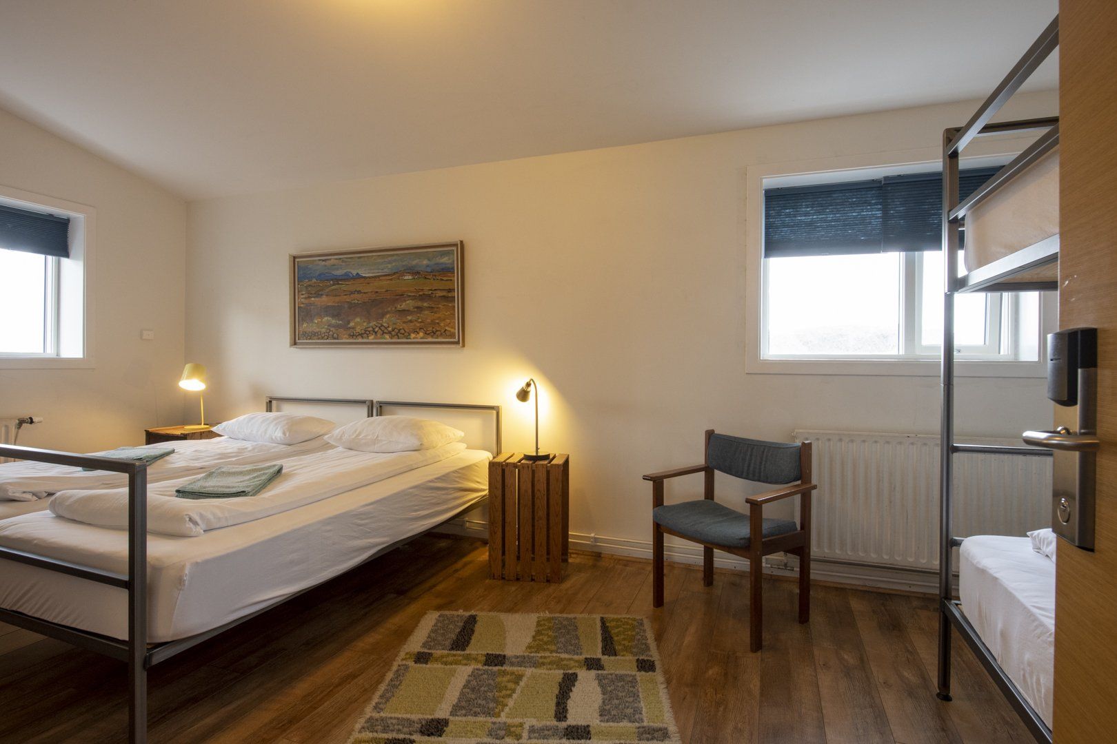 A bedroom with two beds , a chair and a bunk bed.