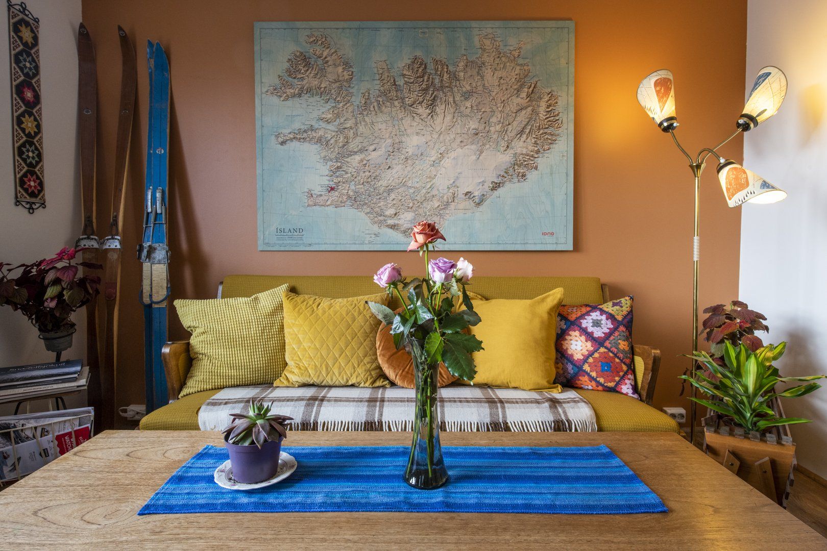A living room with a couch and a table with a vase of flowers on it.