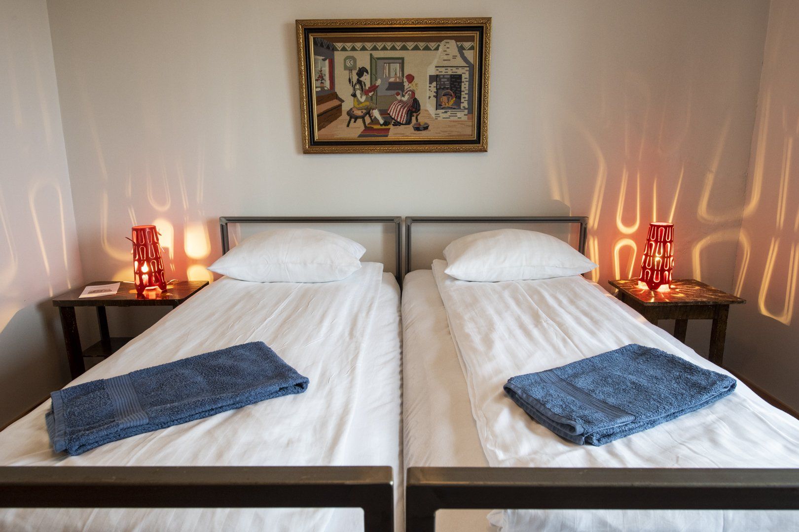 Two beds in a room with a picture on the wall above them