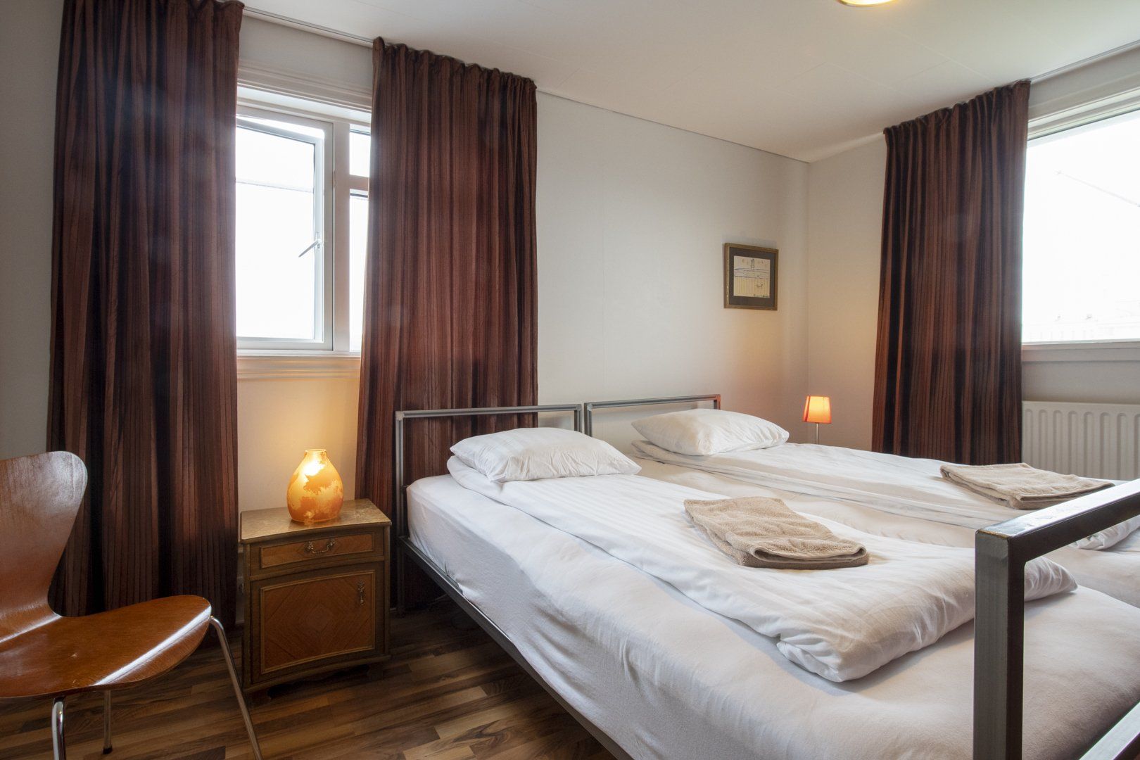 A bedroom with two beds , a chair and a window.