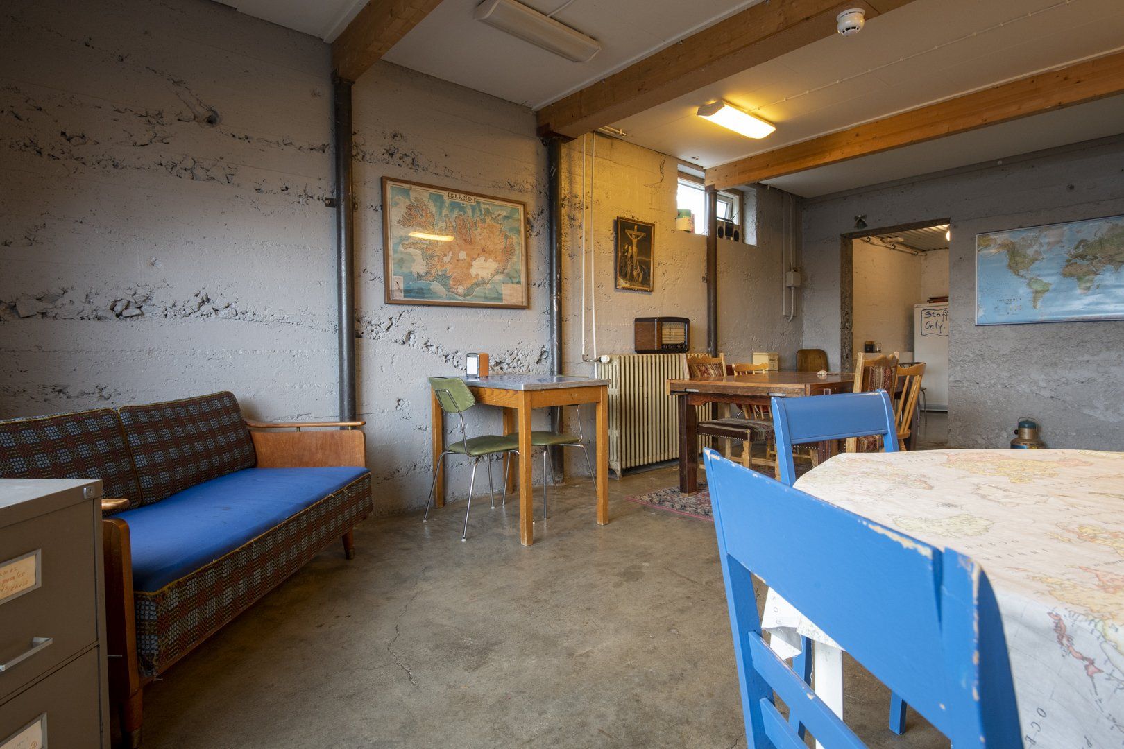A living room with a couch , table , chairs and a map on the wall.