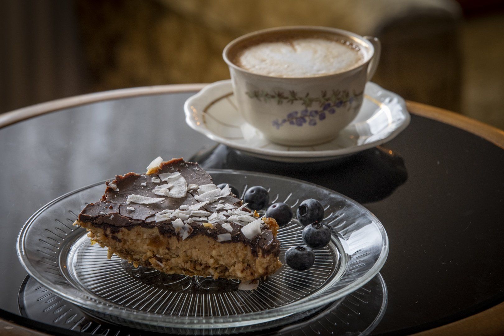There is a piece of cake on a plate next to a cup of coffee.