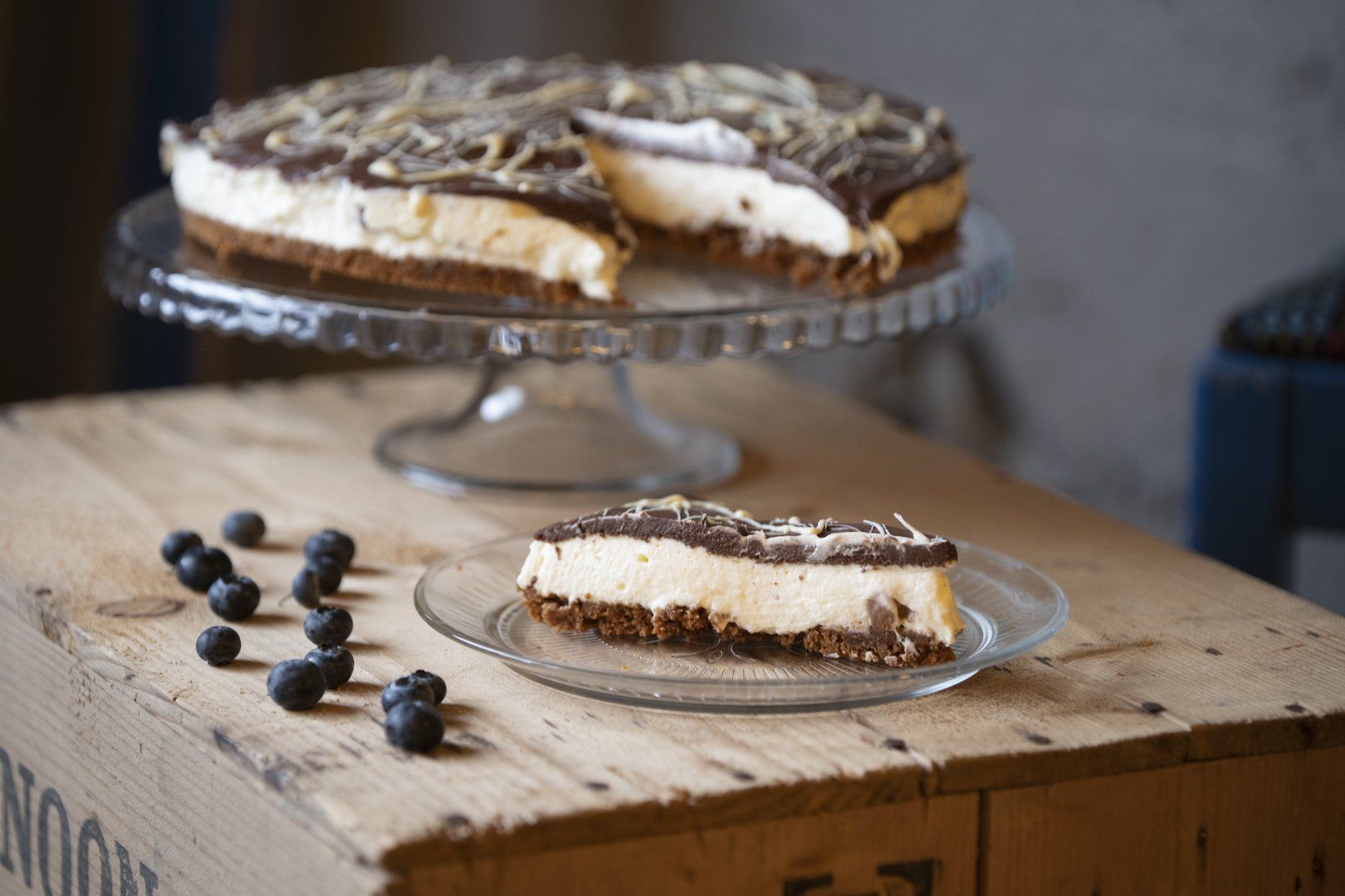 A slice of cheesecake is on a glass plate on a wooden table.
