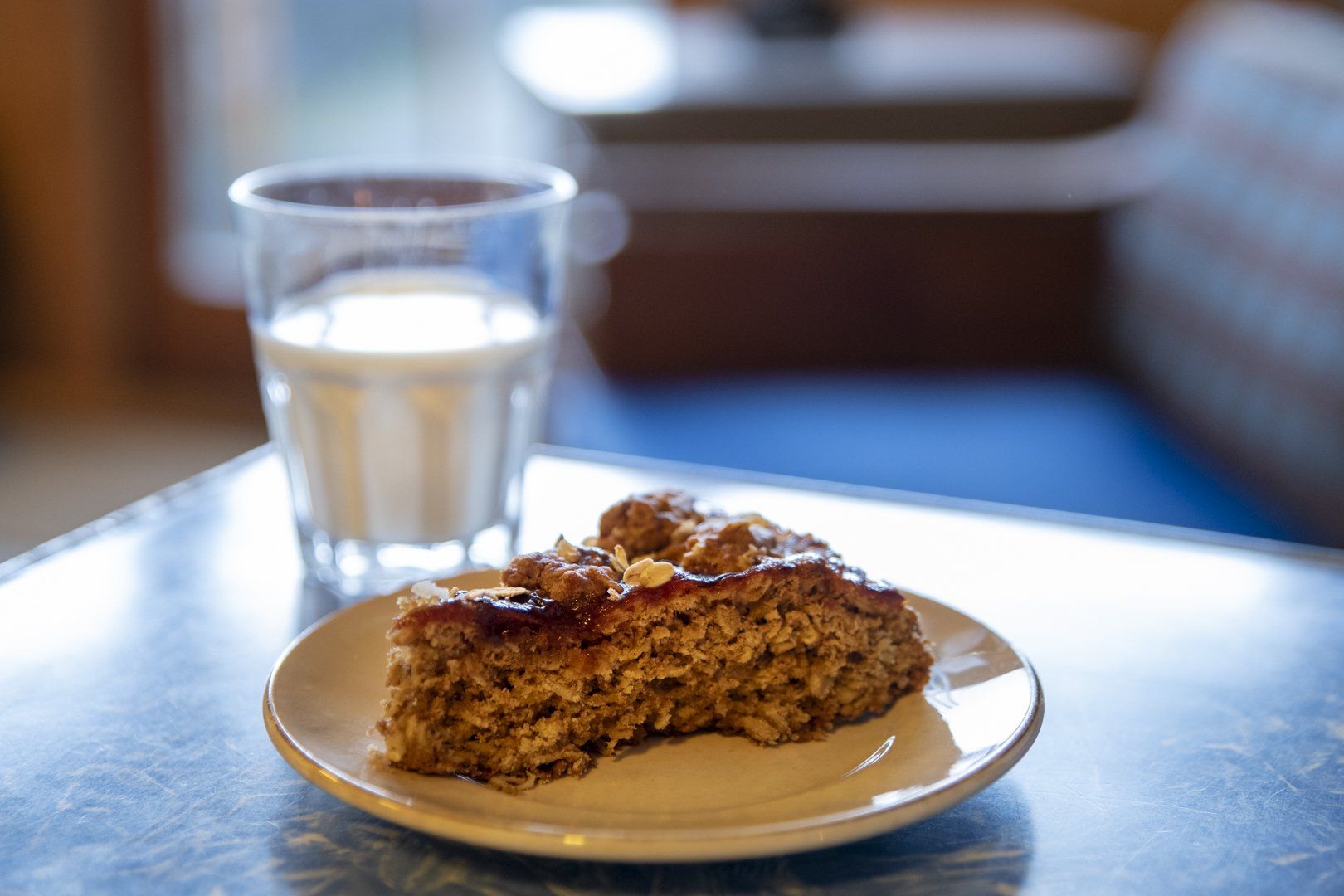 A slice of cake is on a plate next to a glass of milk.