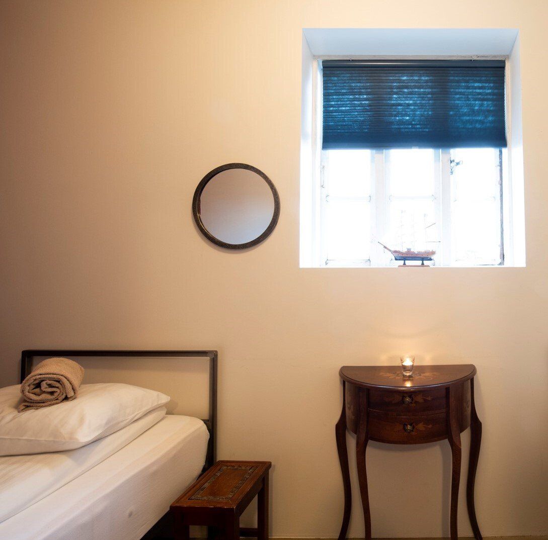 A bedroom with a bed a mirror and a small table