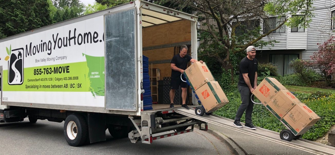 Two men are loading boxes into a moving truck.