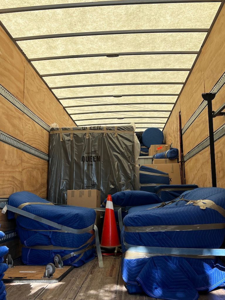 The inside of a moving truck filled with furniture and boxes.
