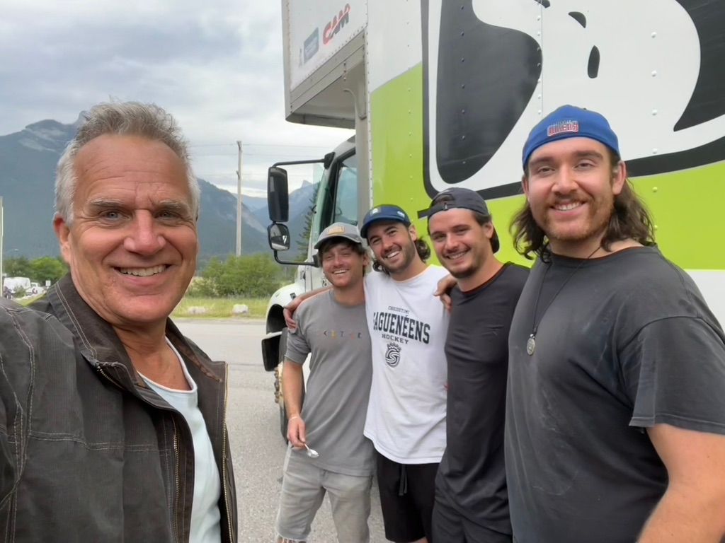 A group of men are posing for a picture in front of a truck.