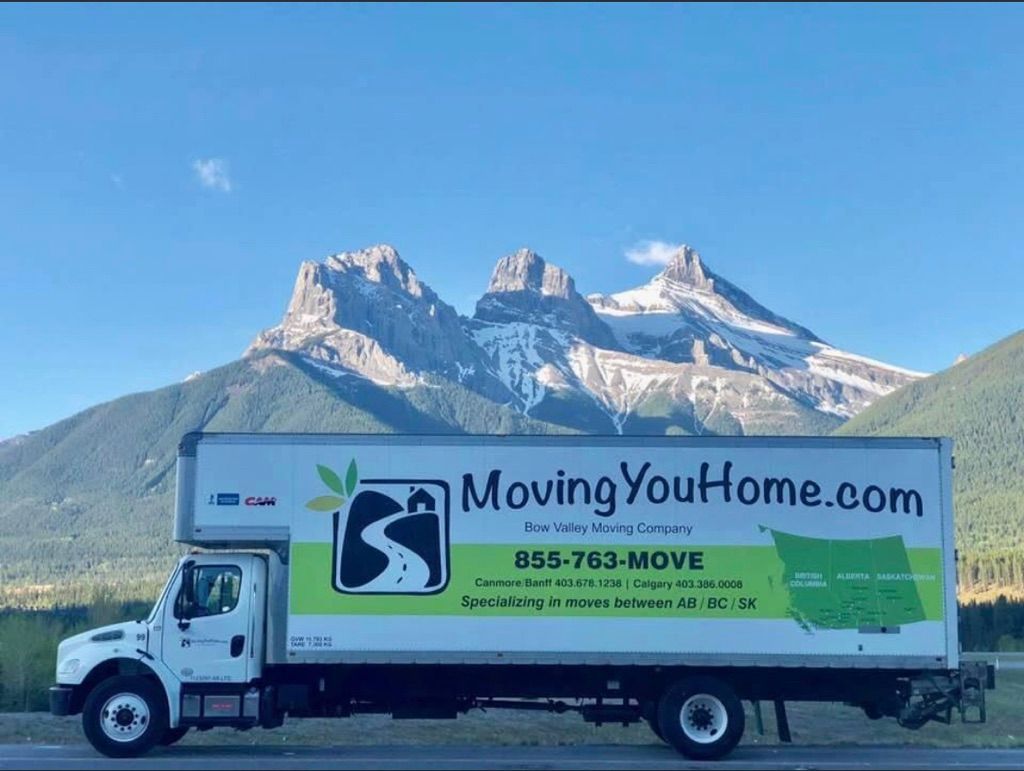 A moving you home truck is parked in front of a mountain.