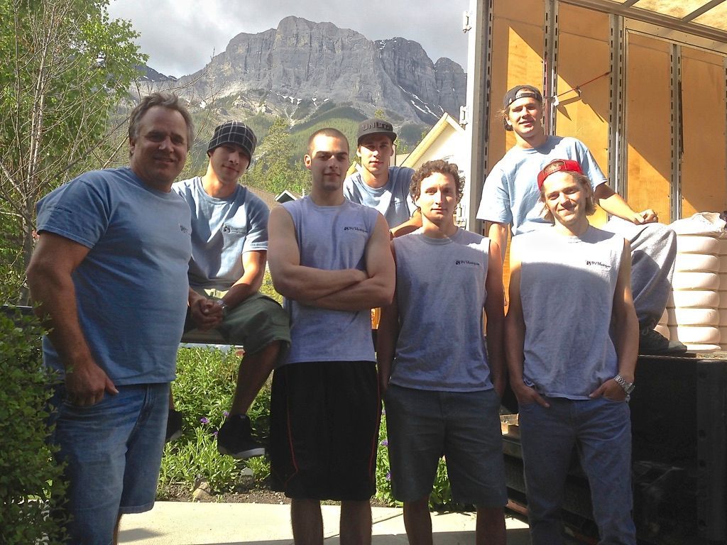 A group of men standing in front of a truck with a mountain in the background