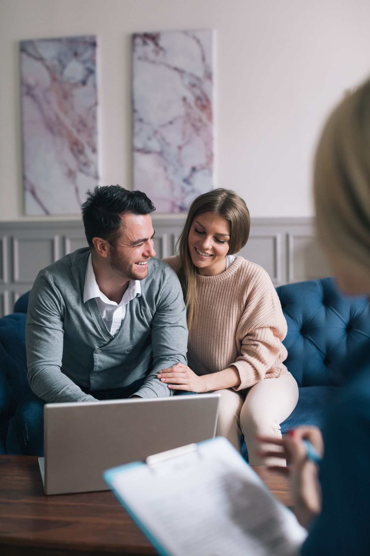Couple smiling on a couch with a laptop in a bright living room during a video call