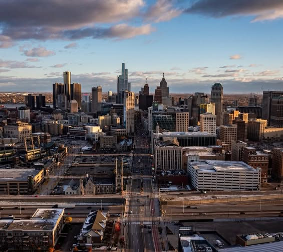City skyline at sunset with tall downtown buildings and a highway in the foreground