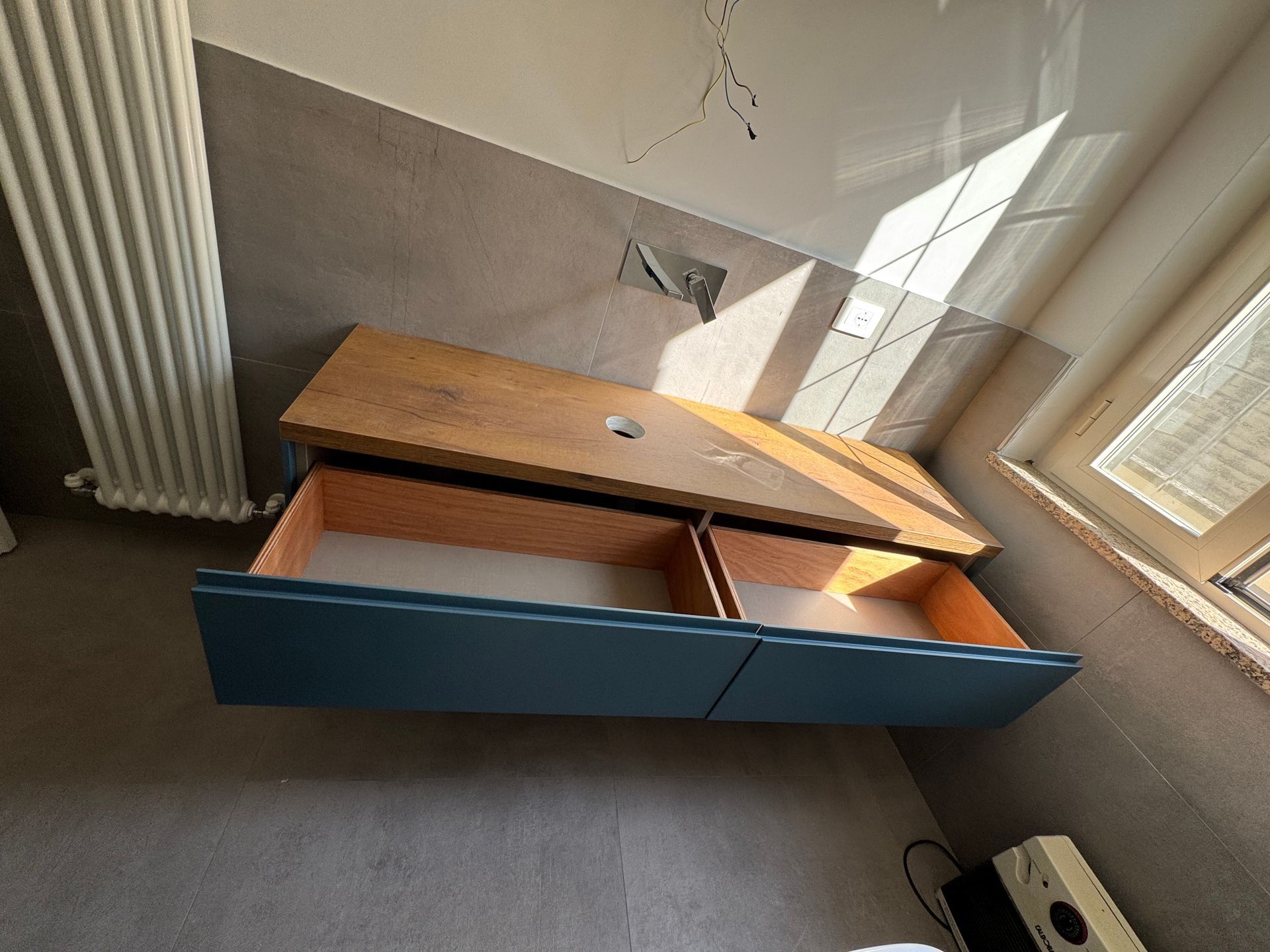 Panca contenitore in legno aperta con pannelli frontali blu in una stanza