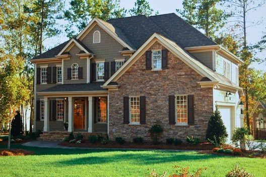 A large brick house with a lush green lawn in front of it.