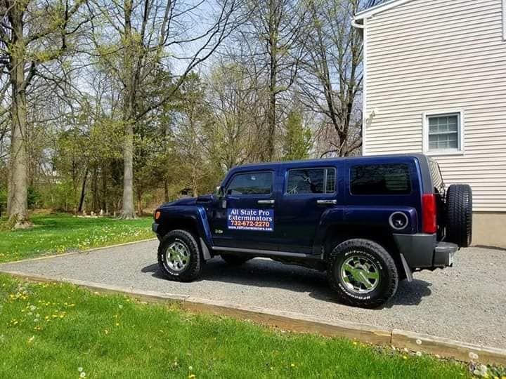 A blue hummer is parked in a driveway in front of a house.