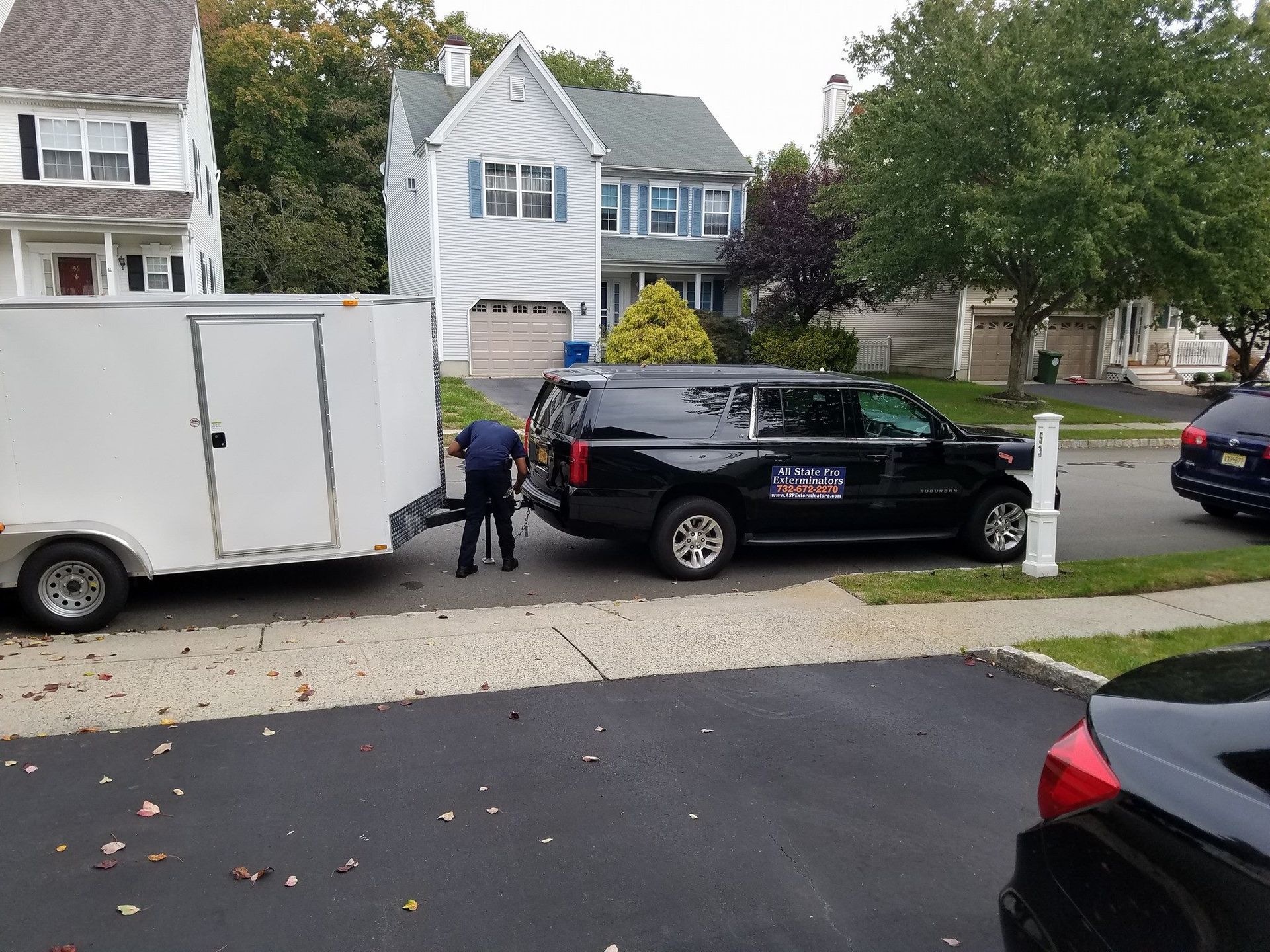 A white trailer is being pulled by a black suv