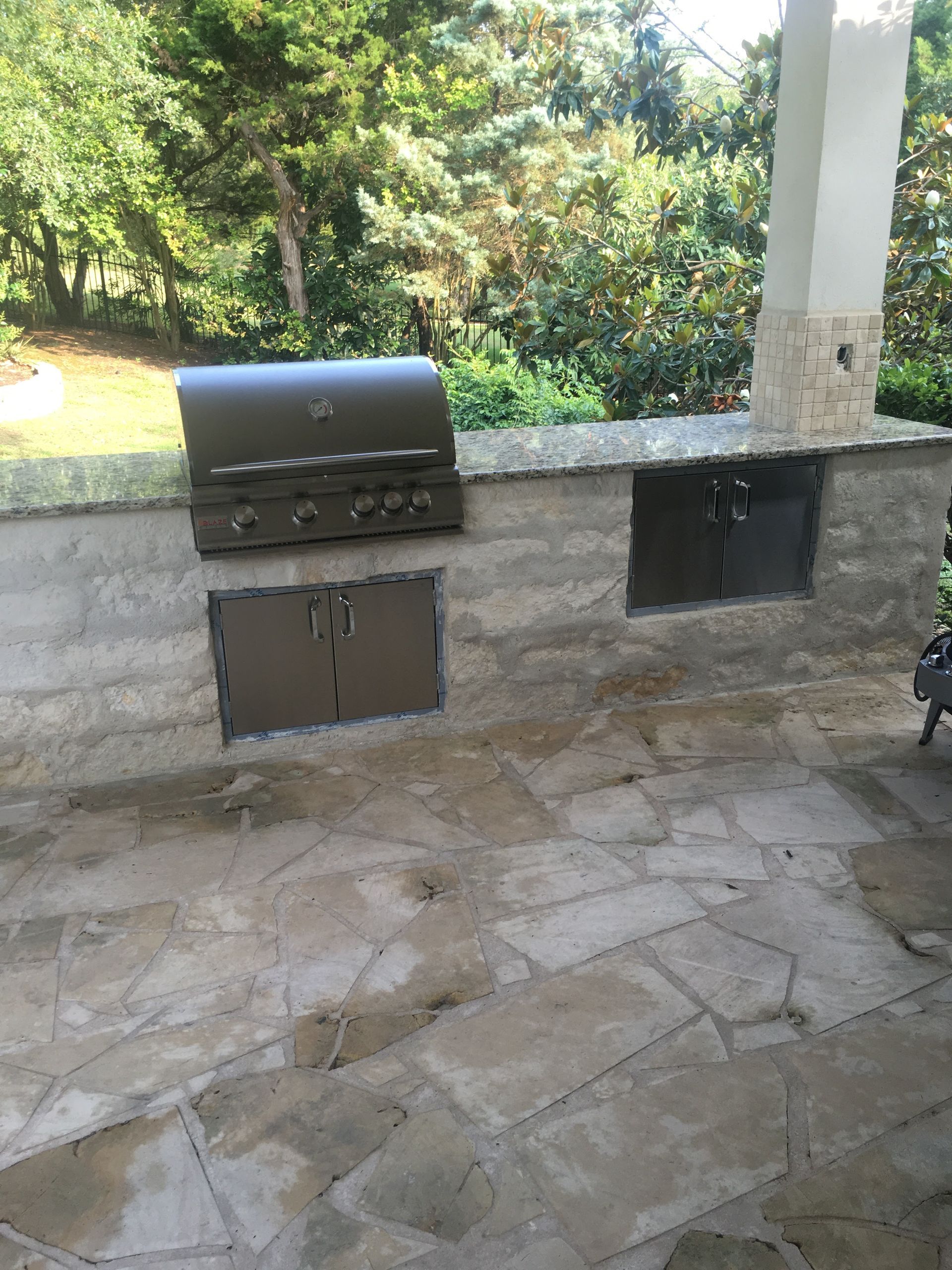 A grill is sitting on top of a stone patio.