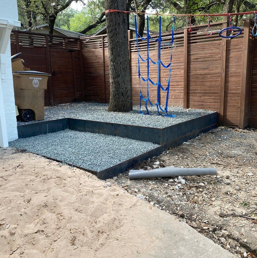 A backyard with gravel and a wooden fence
