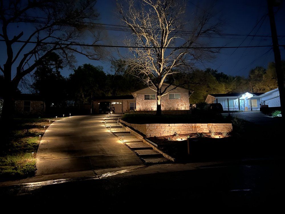 A driveway leading to a house is lit up at night.