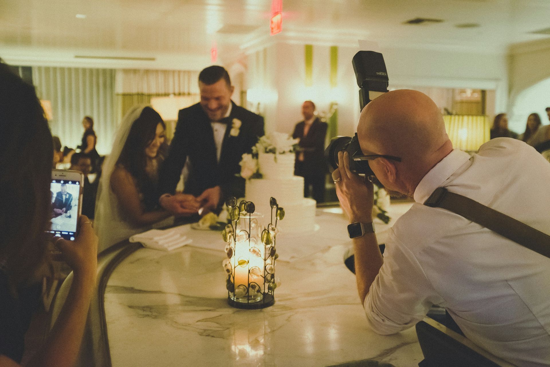 A videographer capturing a bride and groom cutting the cake at a wedding venue in Corsicana, TX.