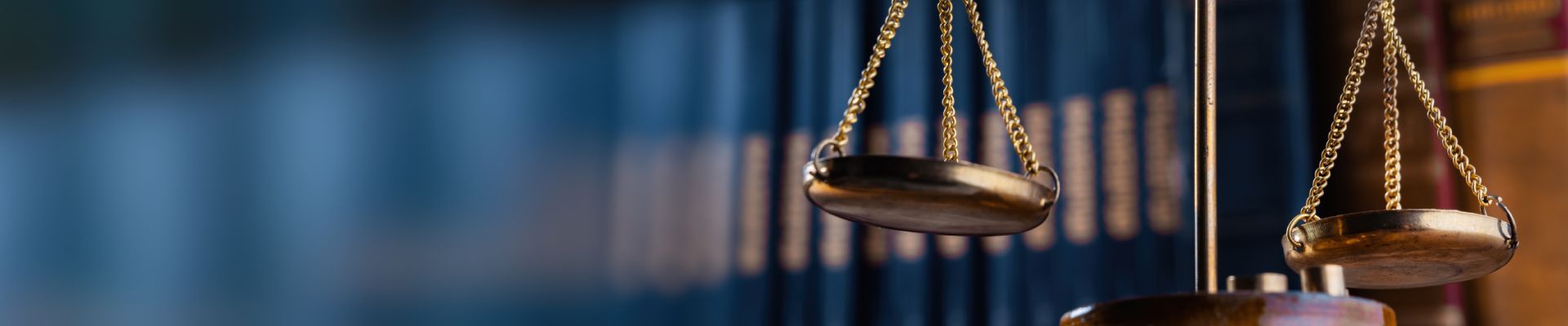 A pair of scales hanging from a pole in front of a blue curtain.